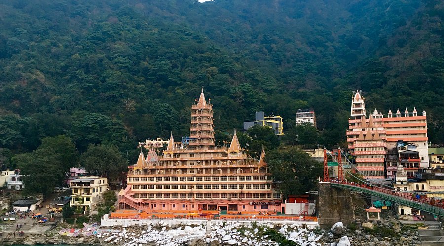 Iron suspension bridge connecting riverbanks, adorned with scenic Ganges views and a lively pedestrian scene. Nearby ashrams and local cuisine enhance the cultural ambiance.