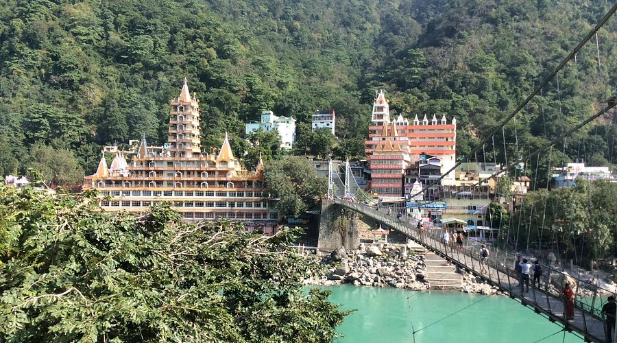 Iron suspension bridge with a historic backdrop, featuring panoramic views of the Ganges and a slight swing sensation, complemented by nearby river activities and cultural markets.